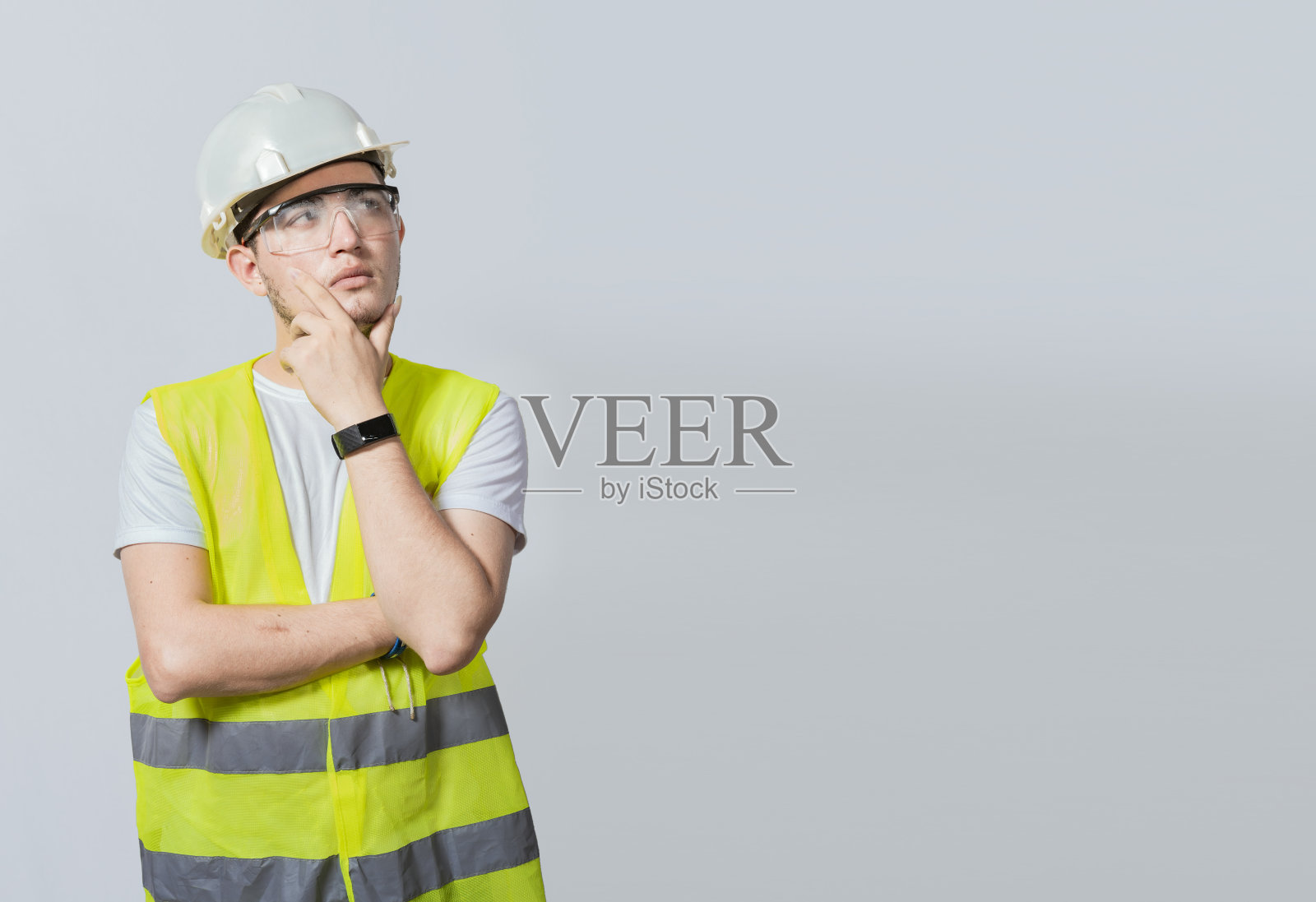 一个沉思的工程师的概念。沉思的建筑工人，手放在下巴上，年轻的建筑工人沉思的肖像，手放在下巴上，白色背景上一个沉思的工程师照片摄影图片