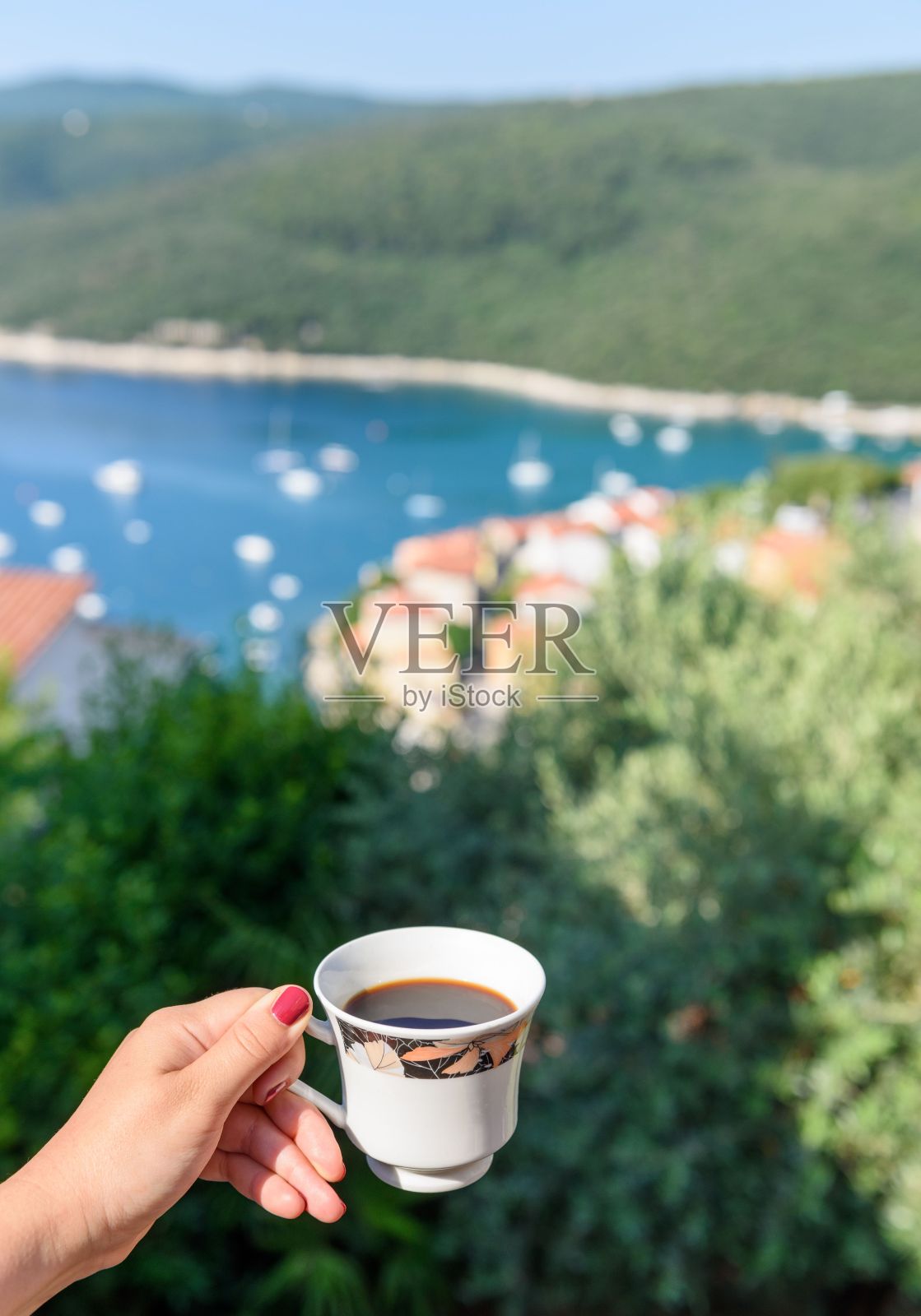在俯瞰克罗地亚拉巴克镇的露台上，一只手拿着一杯咖啡的垂直镜头照片摄影图片