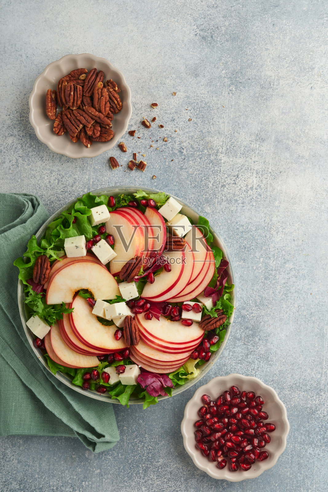 沙拉。新鲜水果沙拉配羊乳酪，苹果，石榴，山核桃和生菜。健康美味的冬季圣诞沙拉。健康均衡的饮食。前视图。照片摄影图片