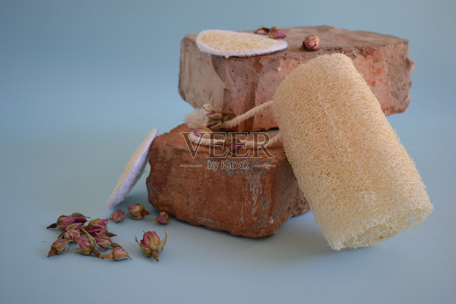 天然丝瓜海绵。用天然海绵在蓝色背景上洗脸。照片摄影图片