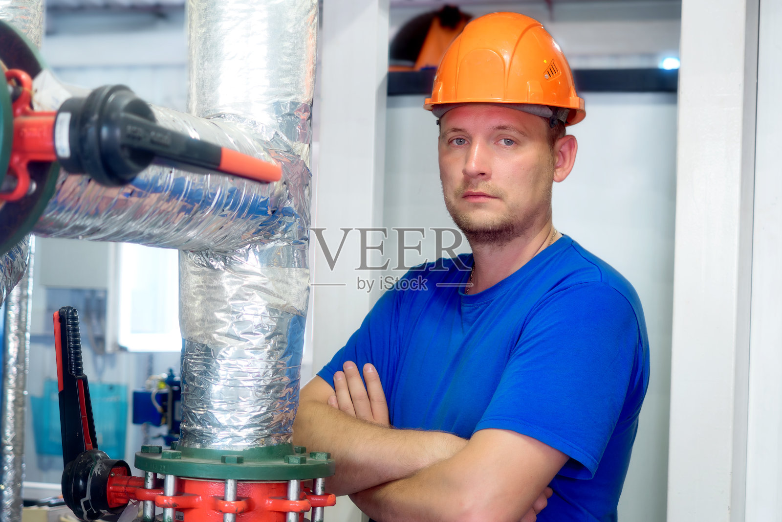 肖像工程师在建筑头盔和工作服的工业背景内的前提。煤气工业工人在锅炉房。欧洲供暖季节的开始。照片摄影图片