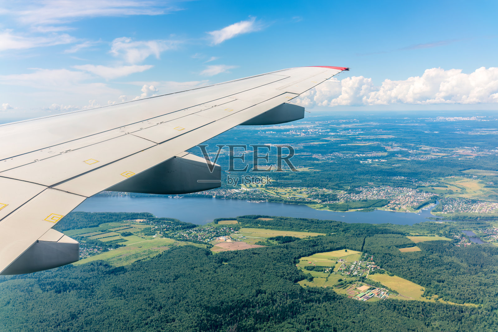 飞机机翼，蓝天和着陆时的绿色土地。飞机窗口视图。照片摄影图片