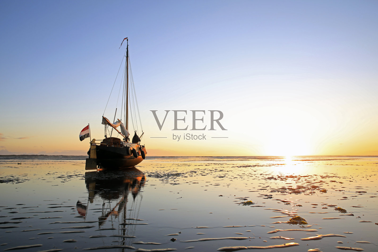 退潮时停泊在沙滩上的帆船照片摄影图片