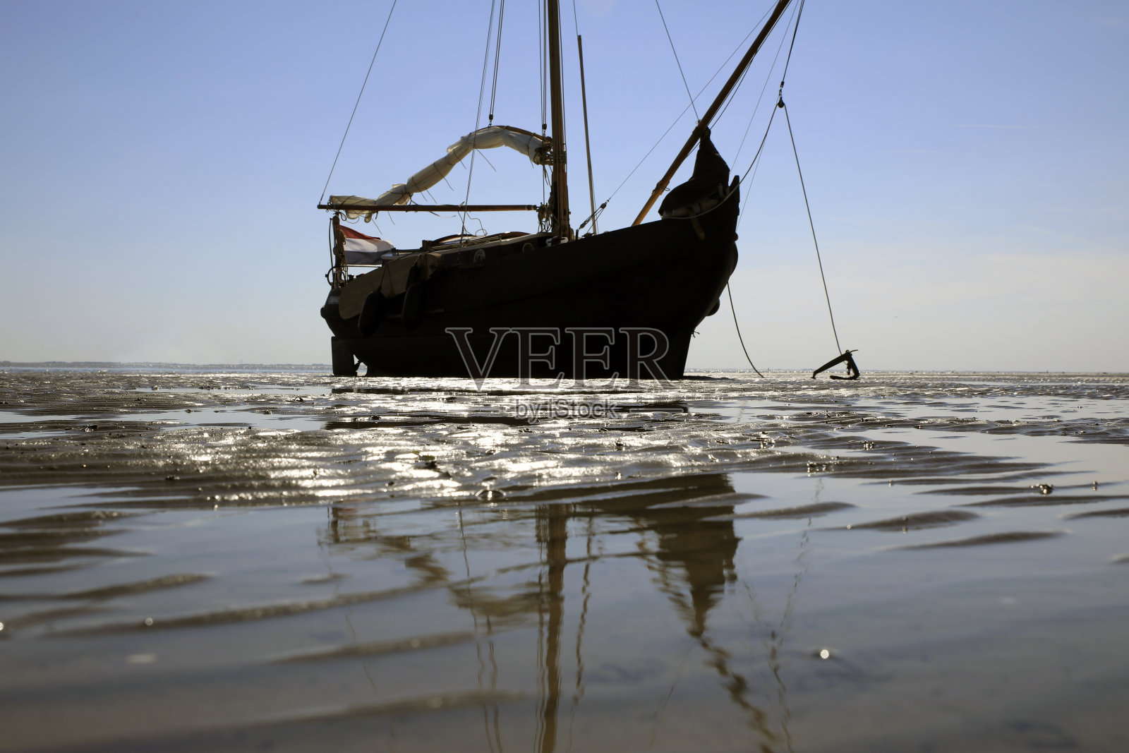 退潮时停泊在沙滩上的帆船照片摄影图片