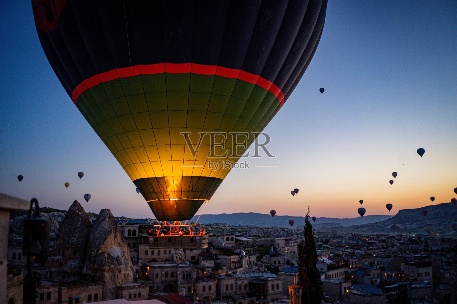 在卡帕多西亚，热气球在日出时飞越山脉和建筑物照片摄影图片