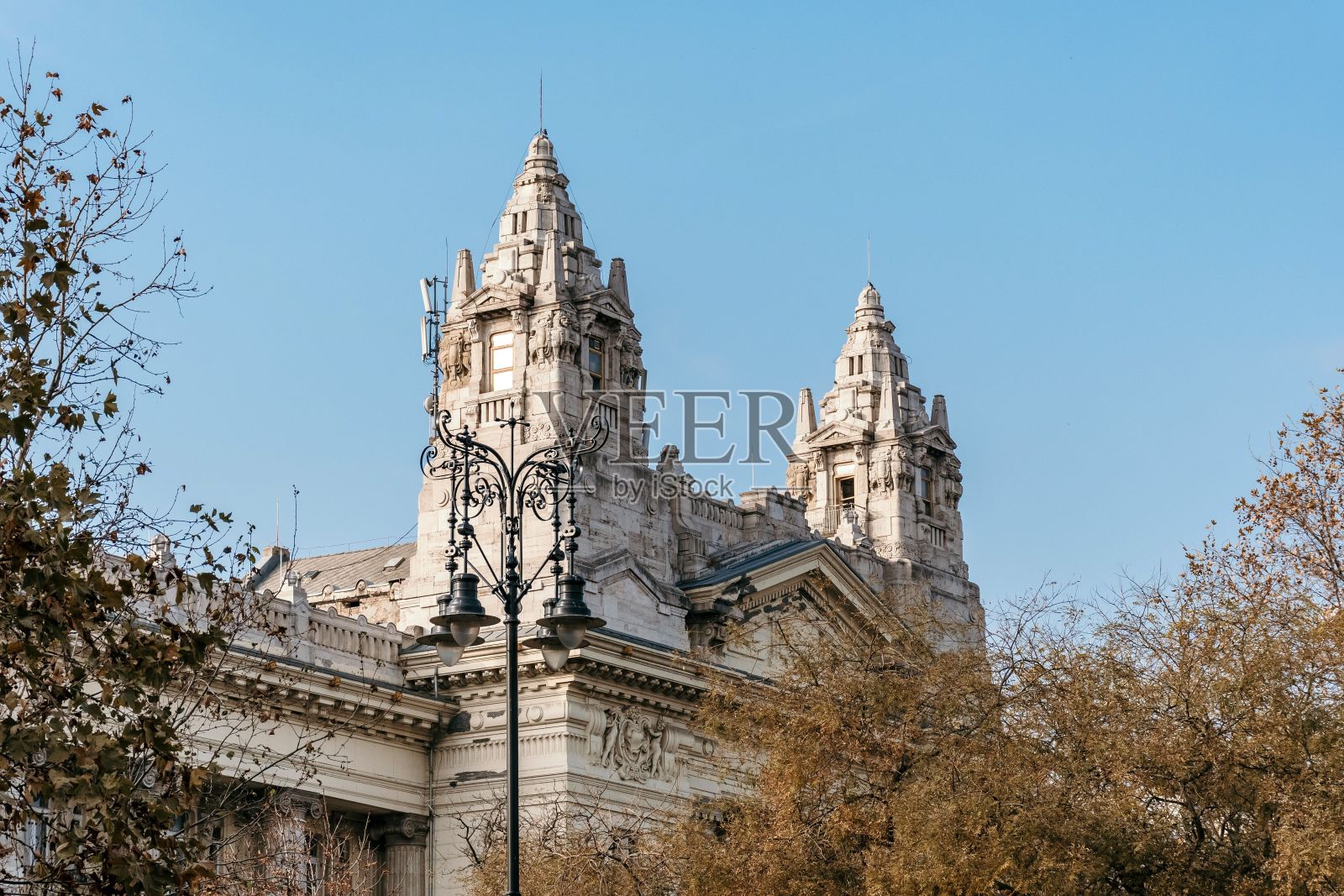 在匈牙利布达佩斯晴朗的天空下，交换宫的外部有秋天的树木照片摄影图片