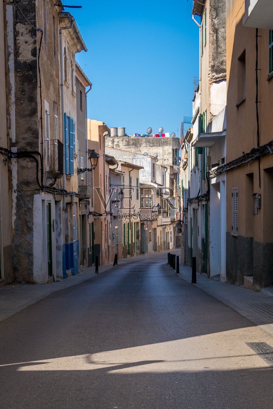 垂直拍摄的街道之间的建筑物在一个晴朗的日子下，一个晴朗的蓝天照片摄影图片