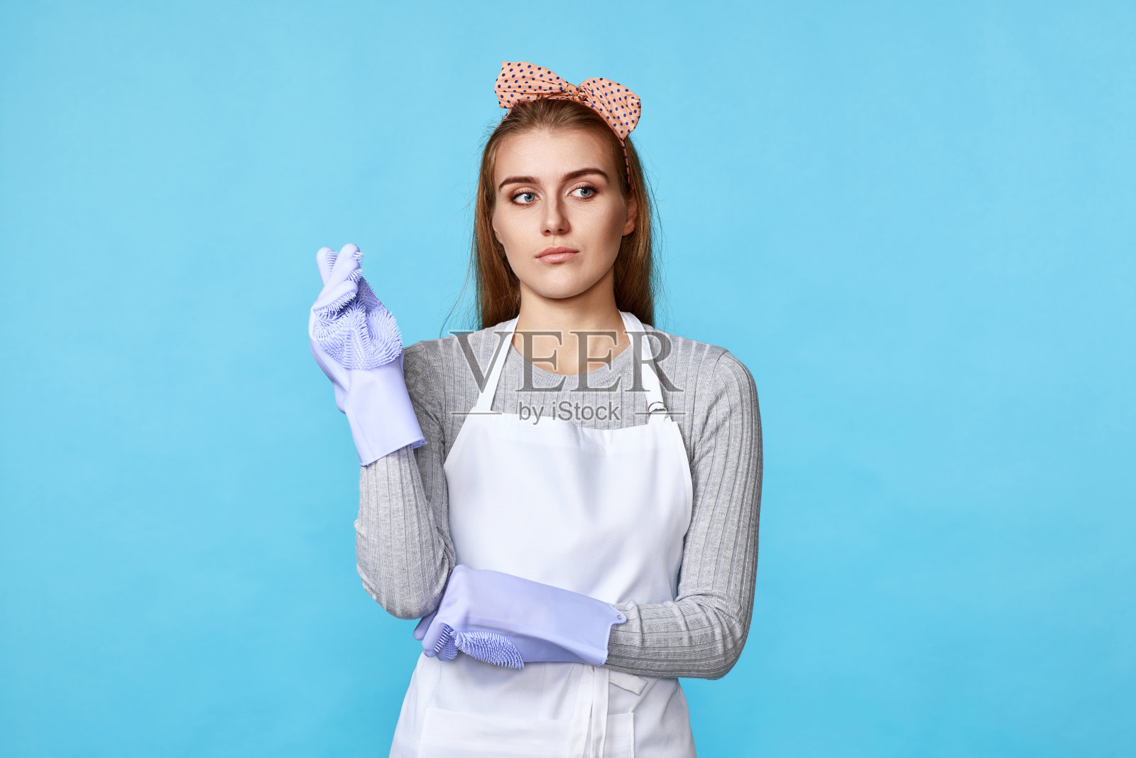 女人戴着橡胶手套和围裙，举起食指照片摄影图片