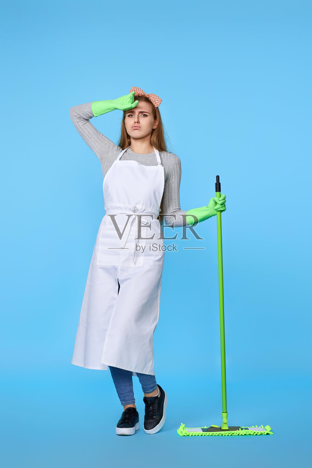 女人戴着橡胶手套和清洁围裙用拖把洗地板照片摄影图片