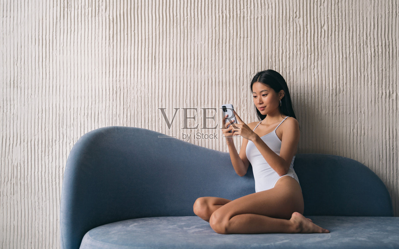 一名亚洲女子坐在家里的沙发上，用在线视频聊天应用程序与朋友聊天照片摄影图片