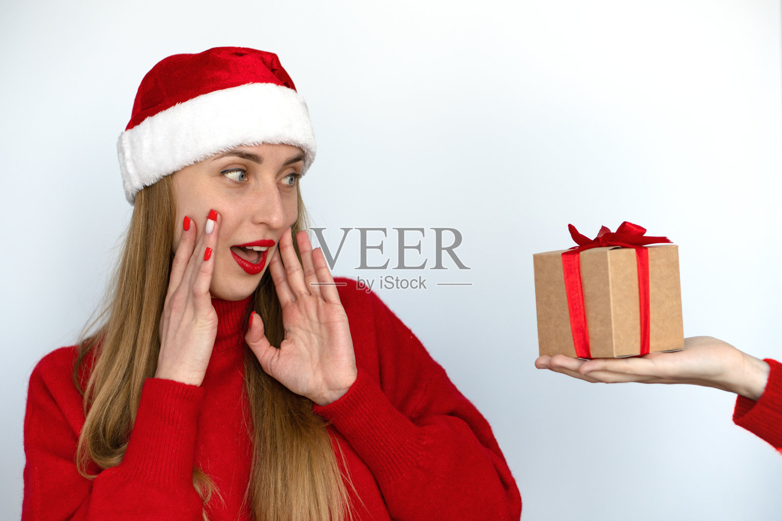 一个打扮成圣诞老人的漂亮女孩很高兴收到圣诞礼物。照片摄影图片