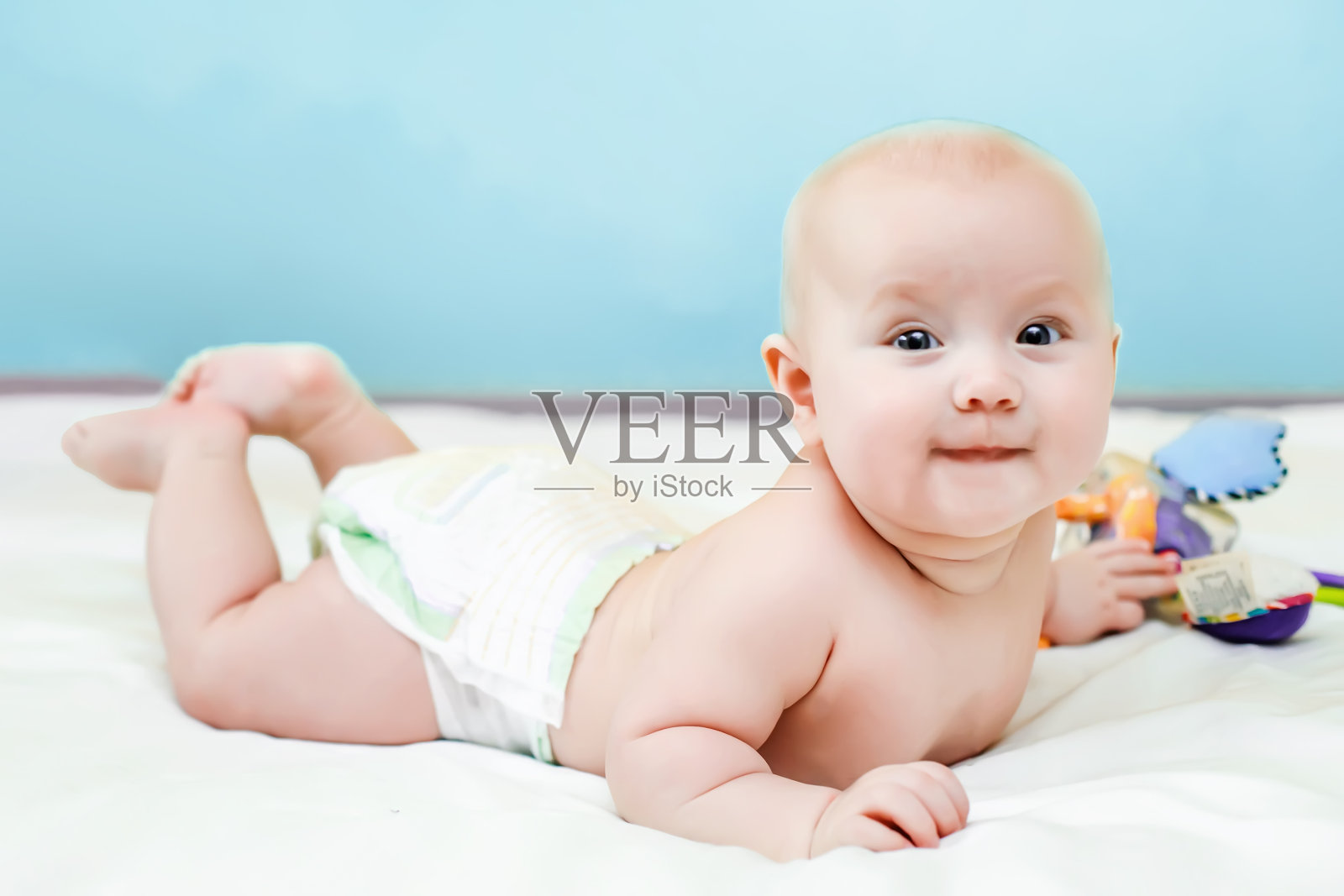 婴儿仰着腿趴在床上。睡觉后把它放在你的肚子上。一个穿着尿布的孩子躺在白色的床上。照片摄影图片