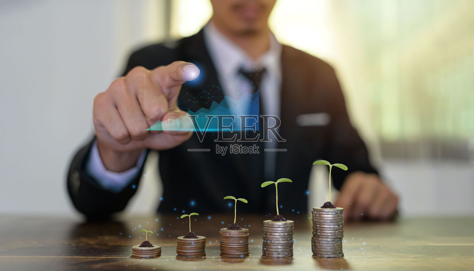 金钱增长的概念-植物在一个桌子上的硬币前一个商人跟踪图表照片摄影图片