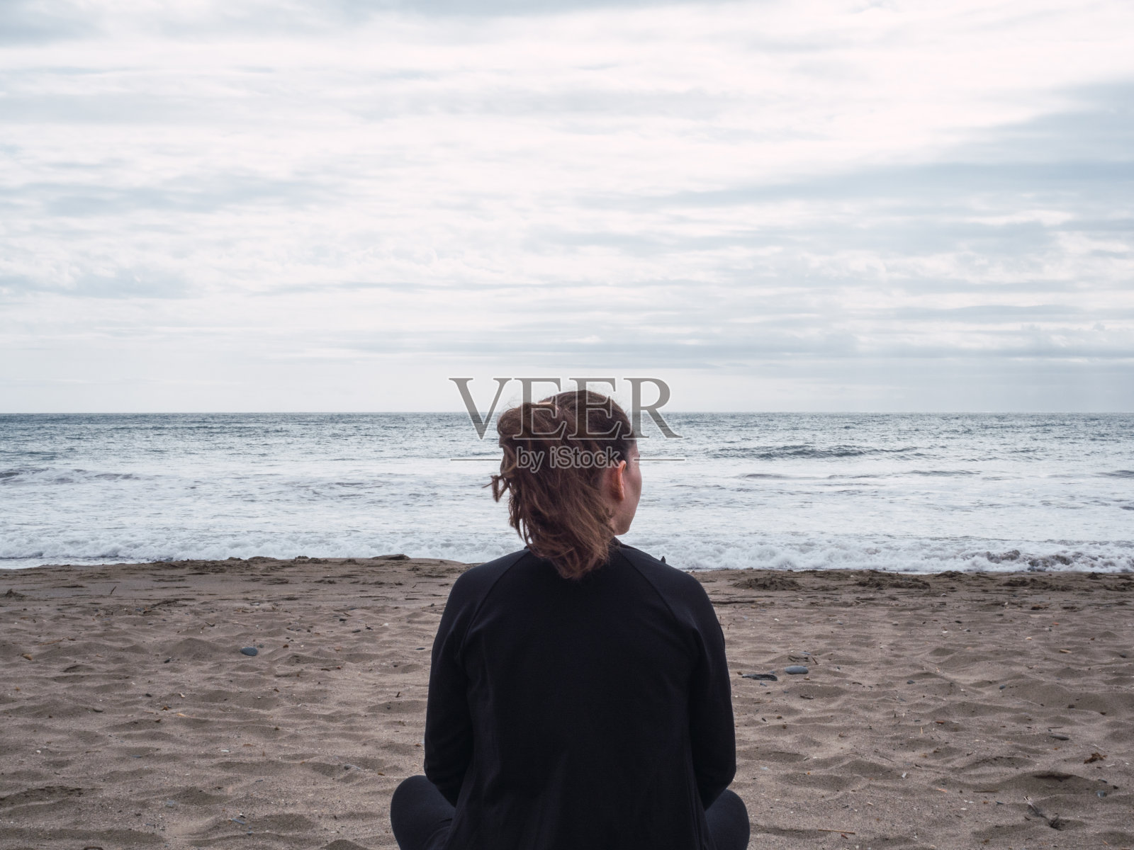 年轻孤独沉思的女人在沙滩上看着大海照片摄影图片