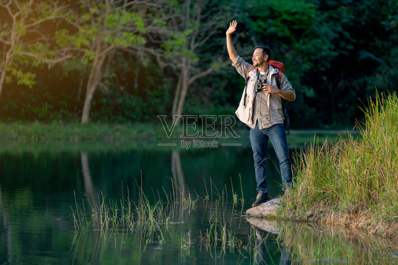 亚洲人在国家公园旅行和露营时，会用手挥手打招呼，期待着湖。照片摄影图片
