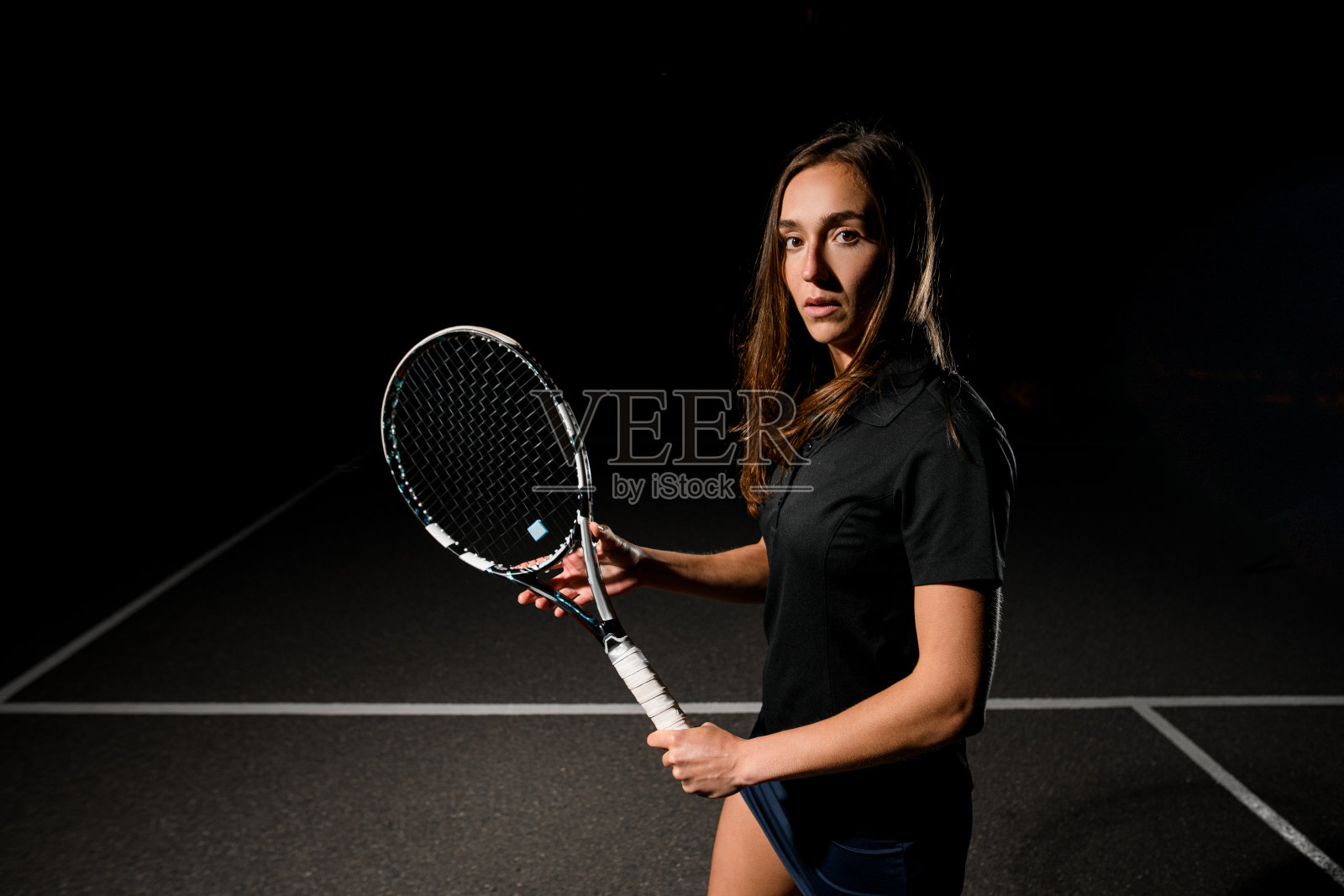 英俊的女子网球运动员肖像，棕色头发，黑色制服，网球拍照片摄影图片