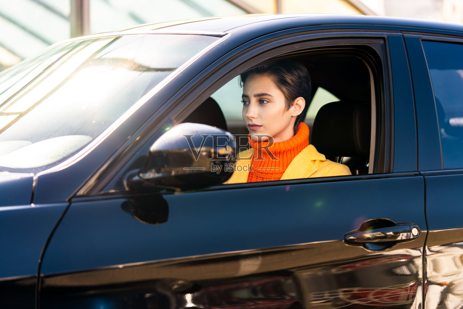 年轻漂亮的短发女子在城市里开车照片摄影图片