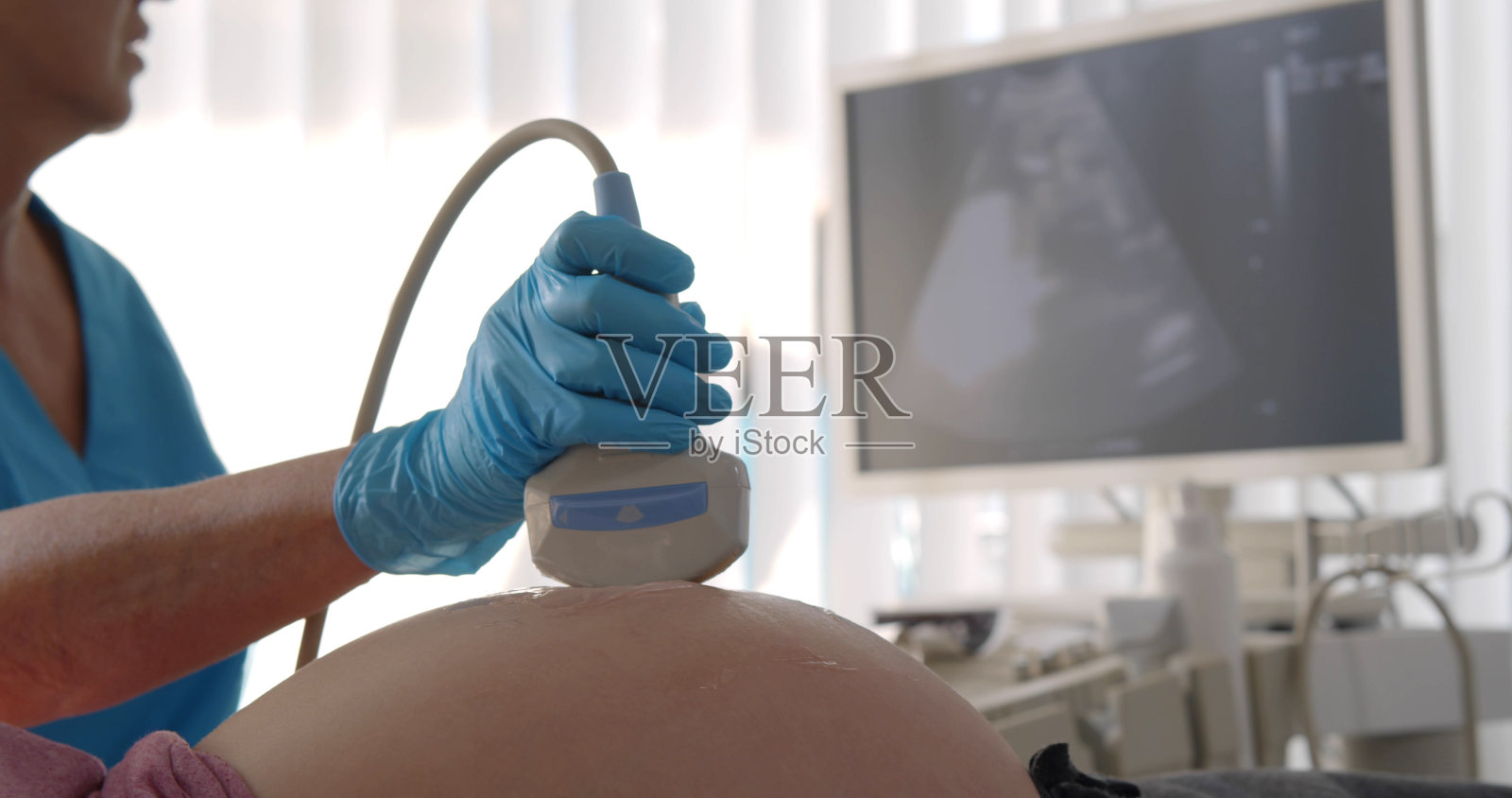 医生在现代诊所对年轻孕妇进行腹部超声检查照片摄影图片