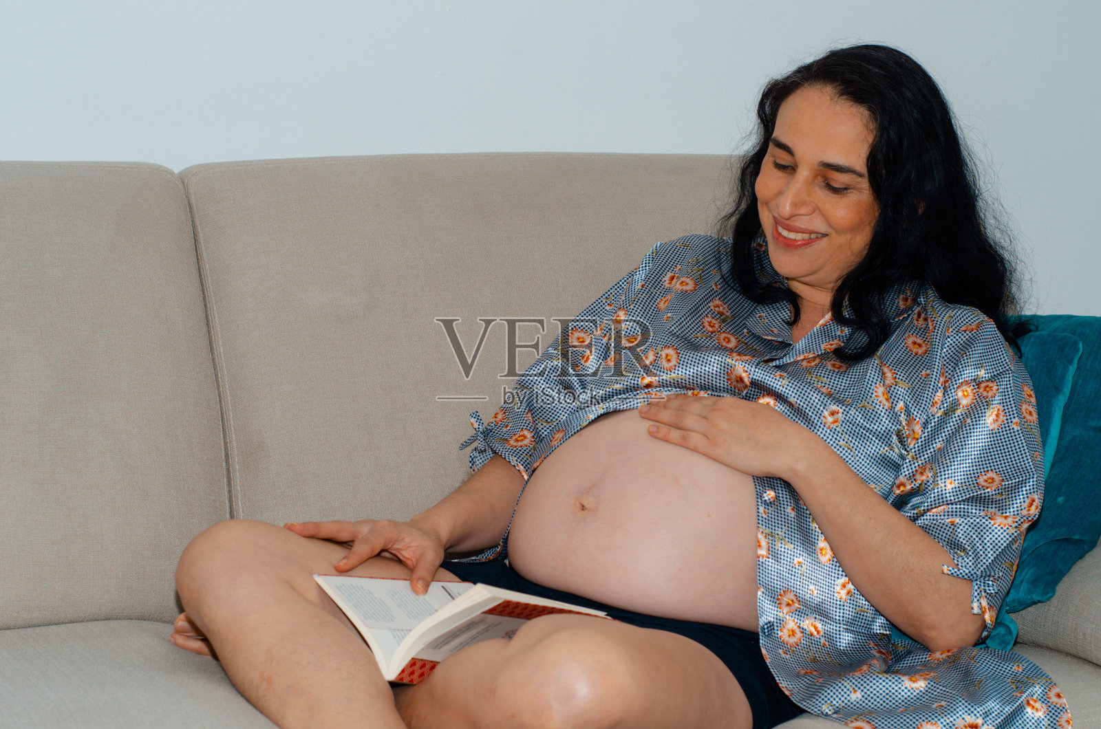 孕妇躺在沙发上看书照片摄影图片