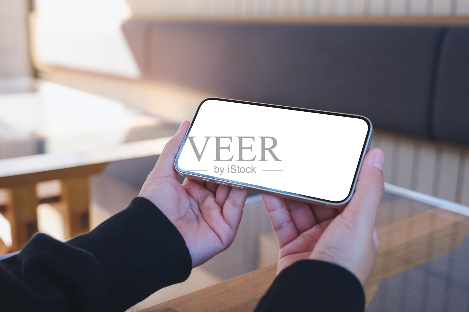 一个女人在咖啡馆里拿着空白桌面的手机的模型图像照片摄影图片