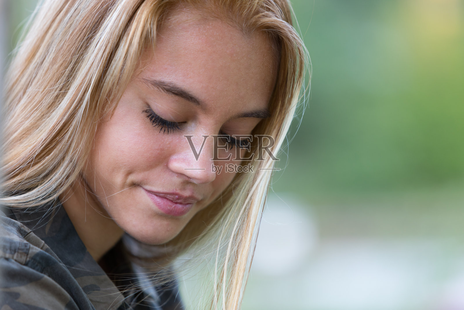 害羞的金发女孩在公园里垂头丧气的凝视照片摄影图片
