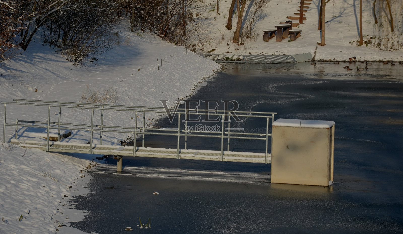 大坝安全溢洪道上的桥梁。石桥，天然铺有灰色平坦的石头。挡土墙的边缘是一道精致的彩色锻铁栏杆。水流下透，镜子反射照片摄影图片