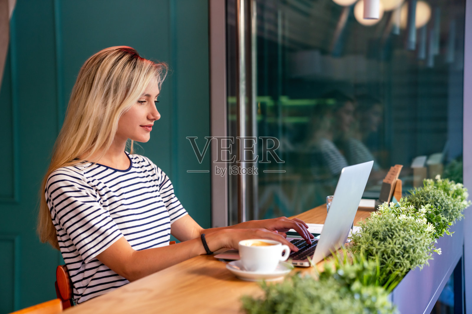 专心工作。漂亮的女人在创意办公室或咖啡馆的笔记本电脑上工作。照片摄影图片