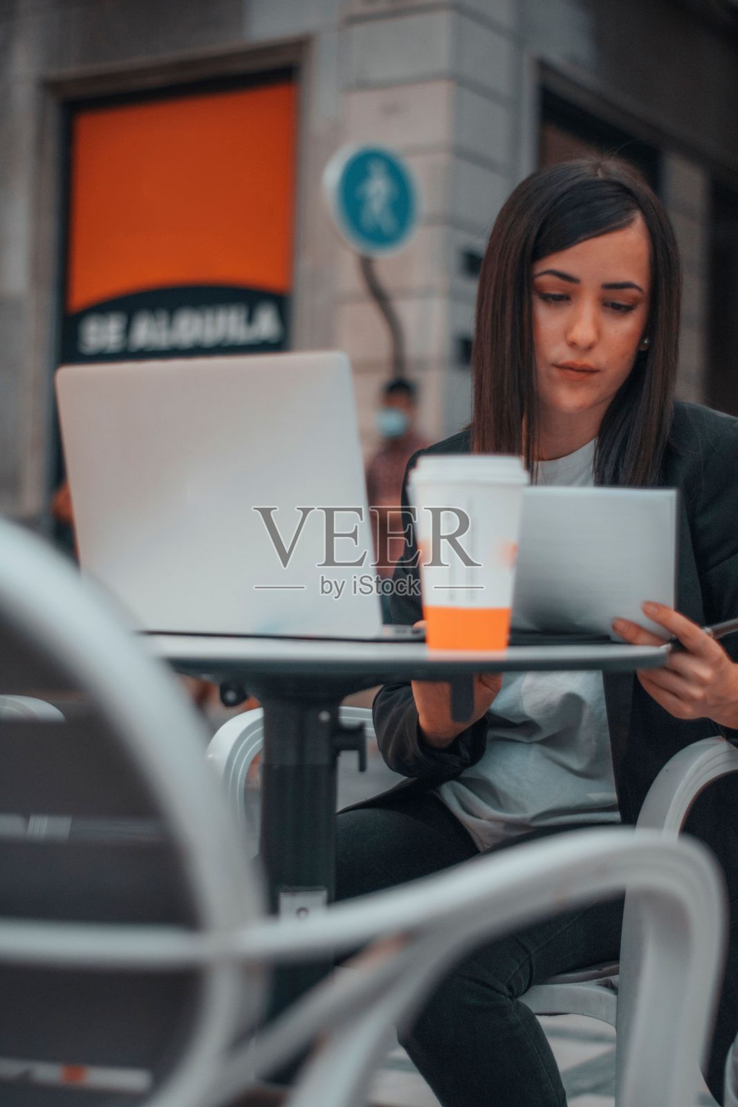 年轻的白人商业妇女阅读一些文件坐在桌子上的笔记本电脑照片摄影图片