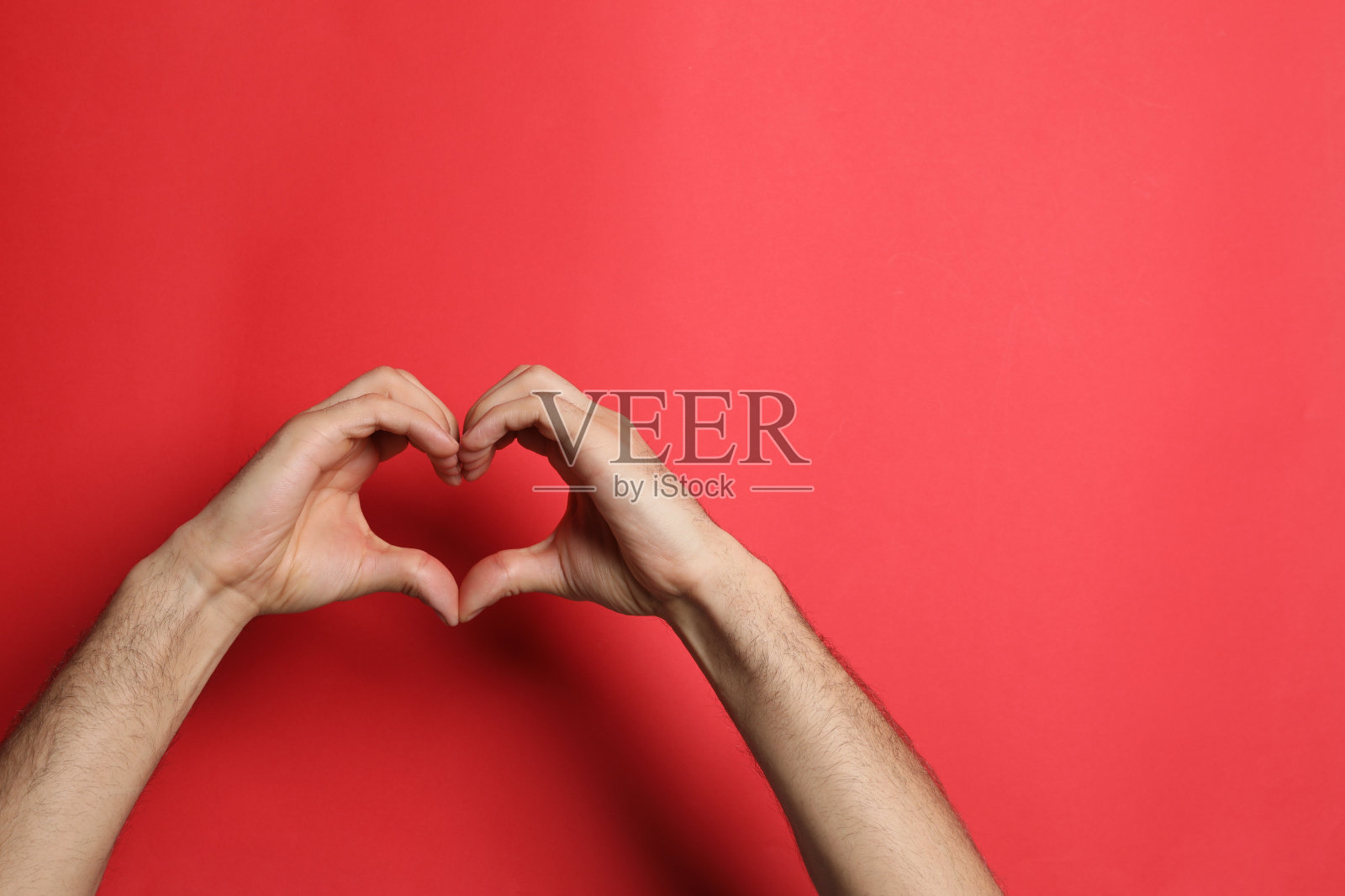男人在红色背景上用手做心脏，特写。文本空间照片摄影图片