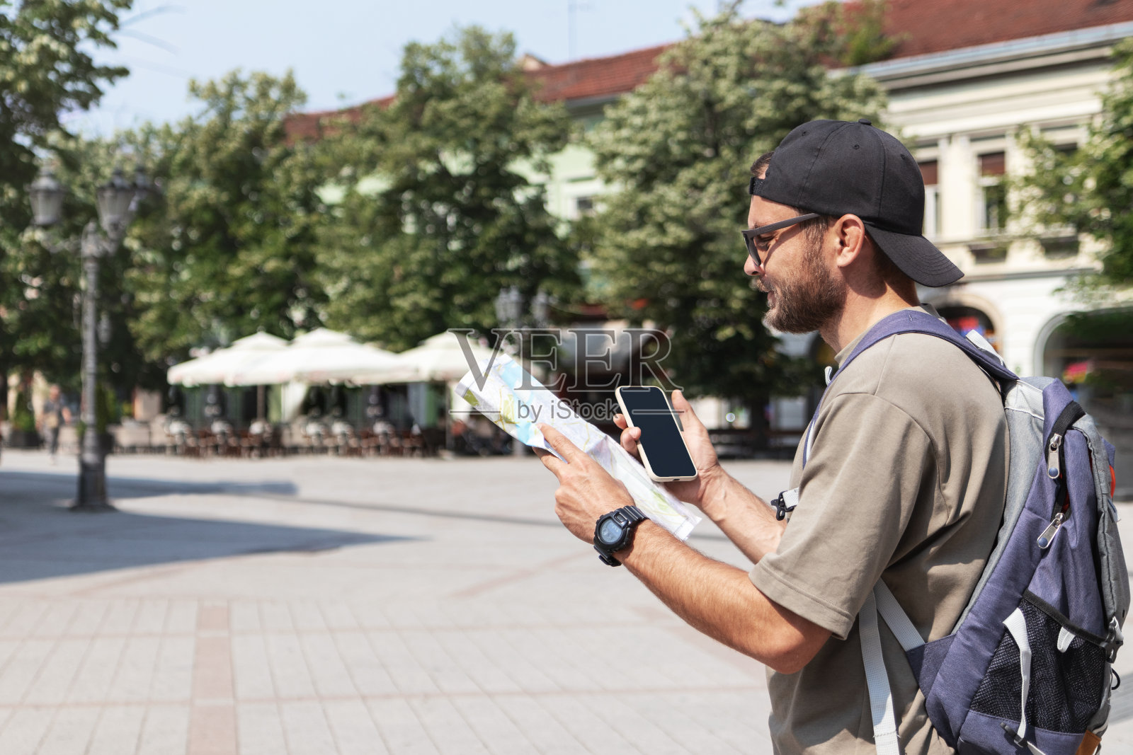 背着双肩包的男性游客用纸质观光地图在镇上闲逛。照片摄影图片