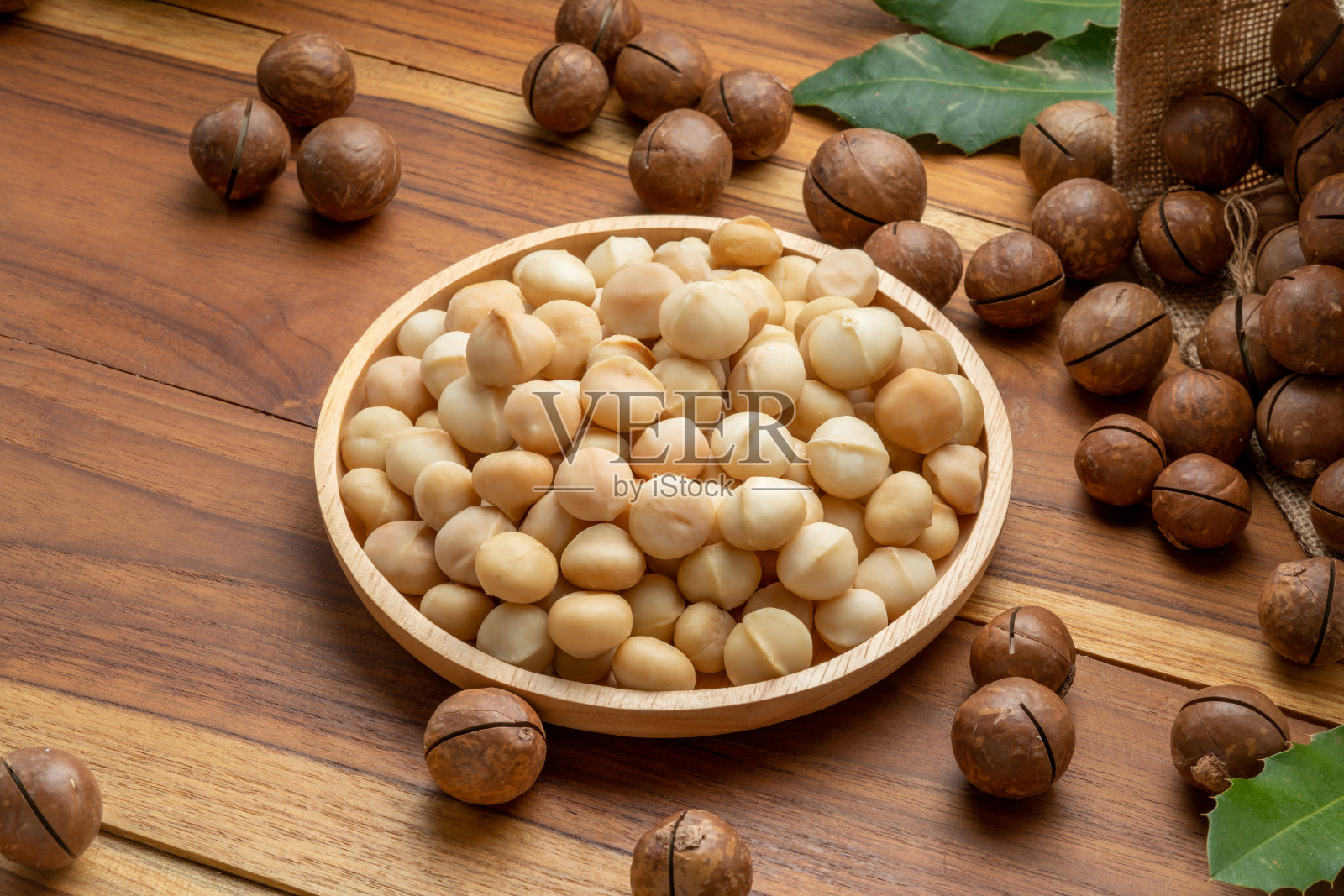 烤澳洲坚果在木盘上的木制背景，澳洲坚果在木制背景。照片摄影图片