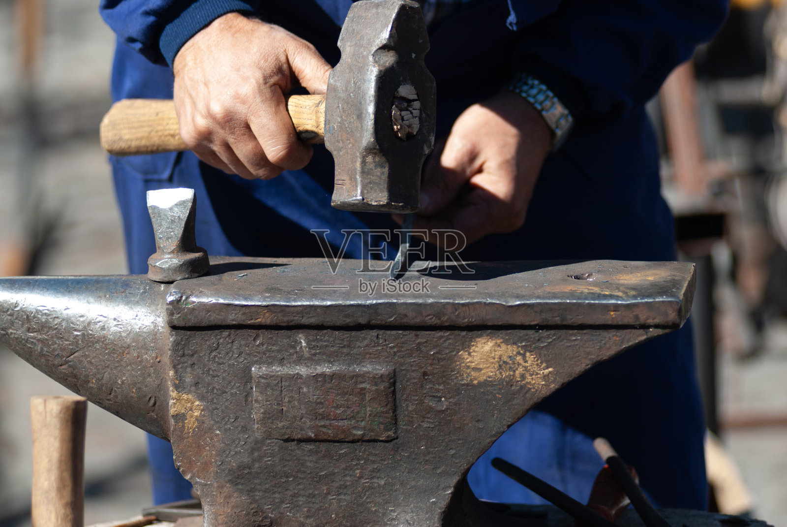 在金属铁砧上敲打的铁匠照片摄影图片
