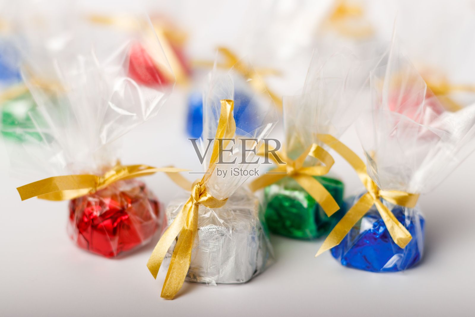 彩色糖果的特写镜头，白色背景上漂亮地用金色丝带包裹着照片摄影图片