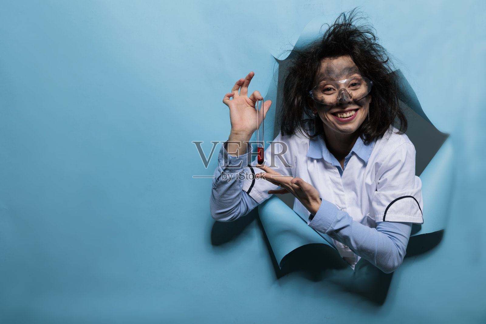 带着滑稽表情的疯狂化学家拿着装满化合物的烧瓶。照片摄影图片