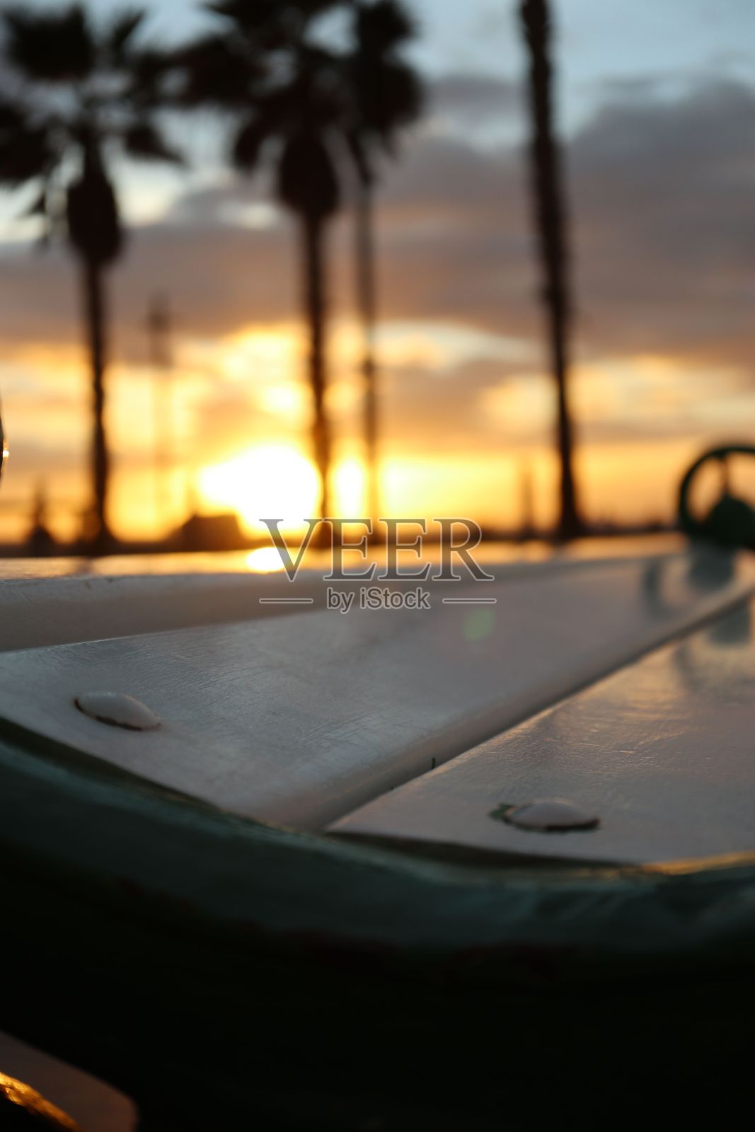 海滩日落，棕榈树在白色长凳和剪影前照片摄影图片