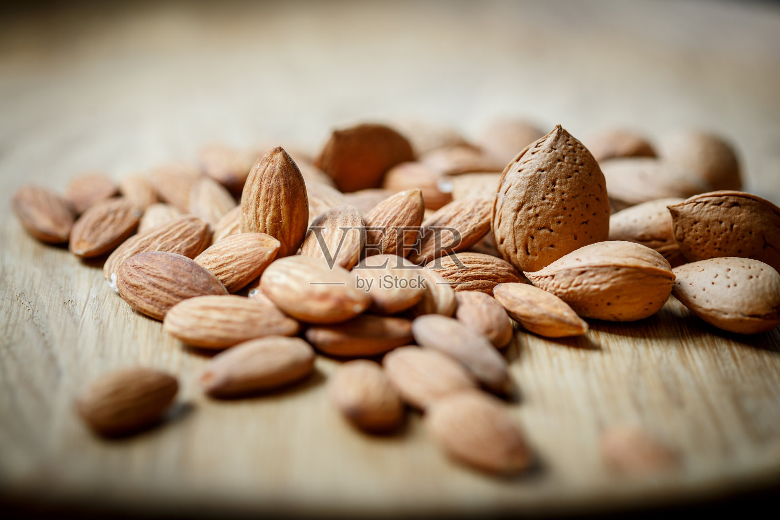 剥了皮的生杏仁和带壳的杏仁在木制背景上。照片摄影图片