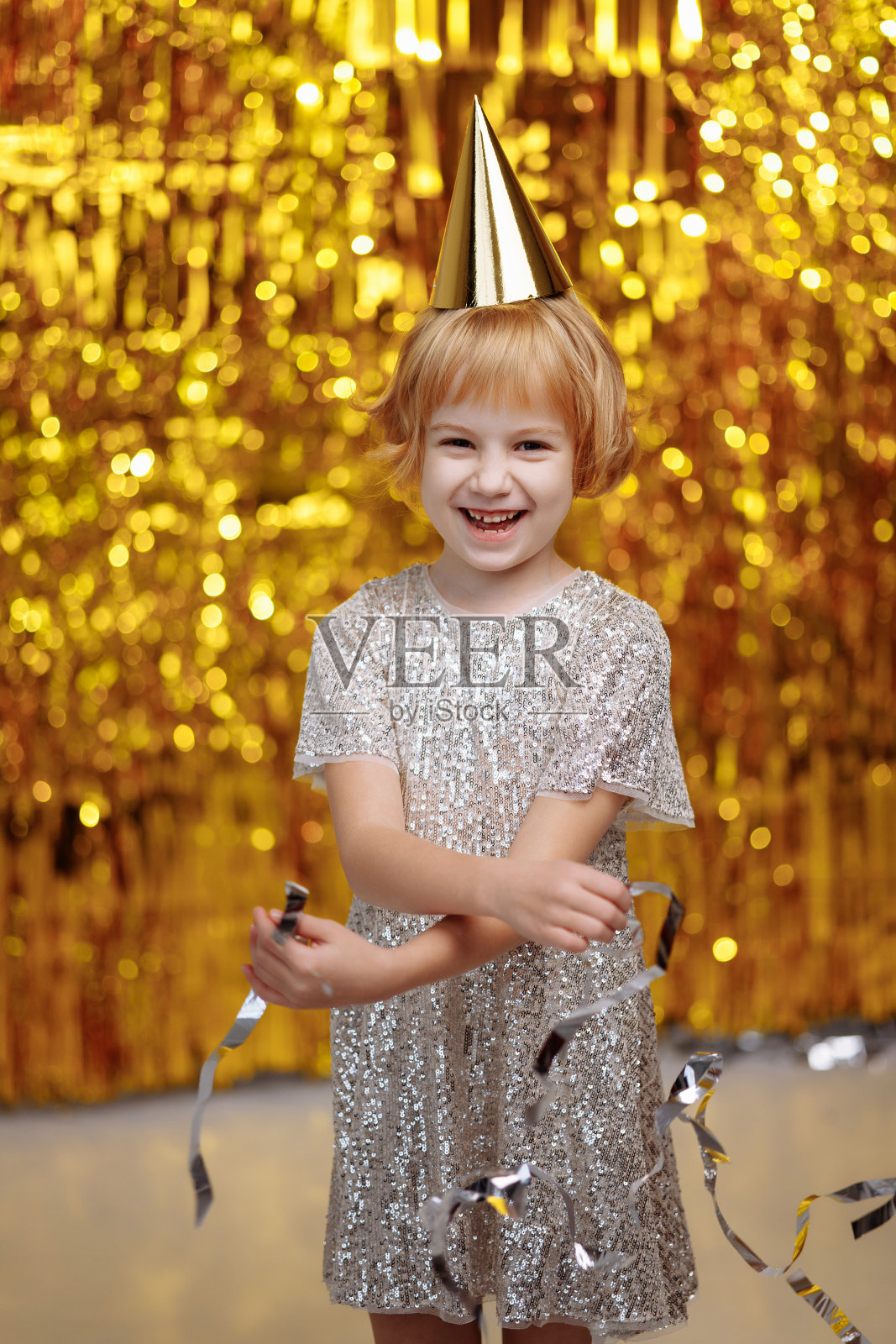 一个戴着节日帽，穿着闪亮裙子的孩子。照片摄影图片
