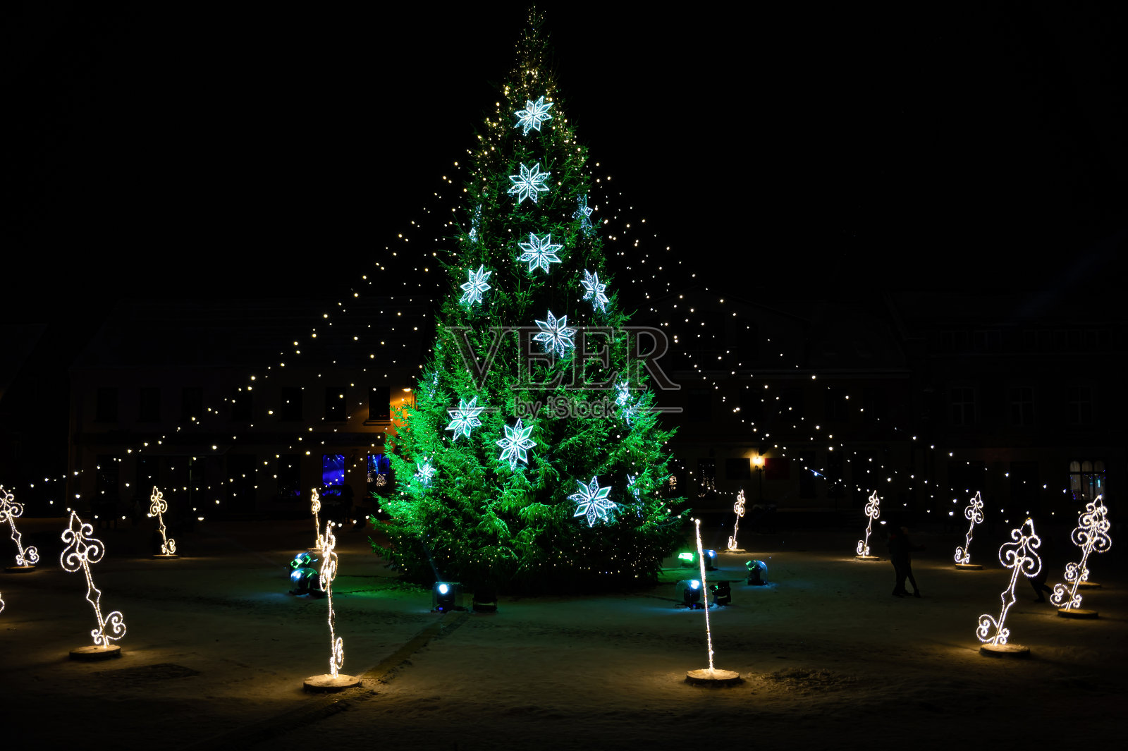 夜晚，小镇广场上装饰着彩灯和装饰品的圣诞树照片摄影图片