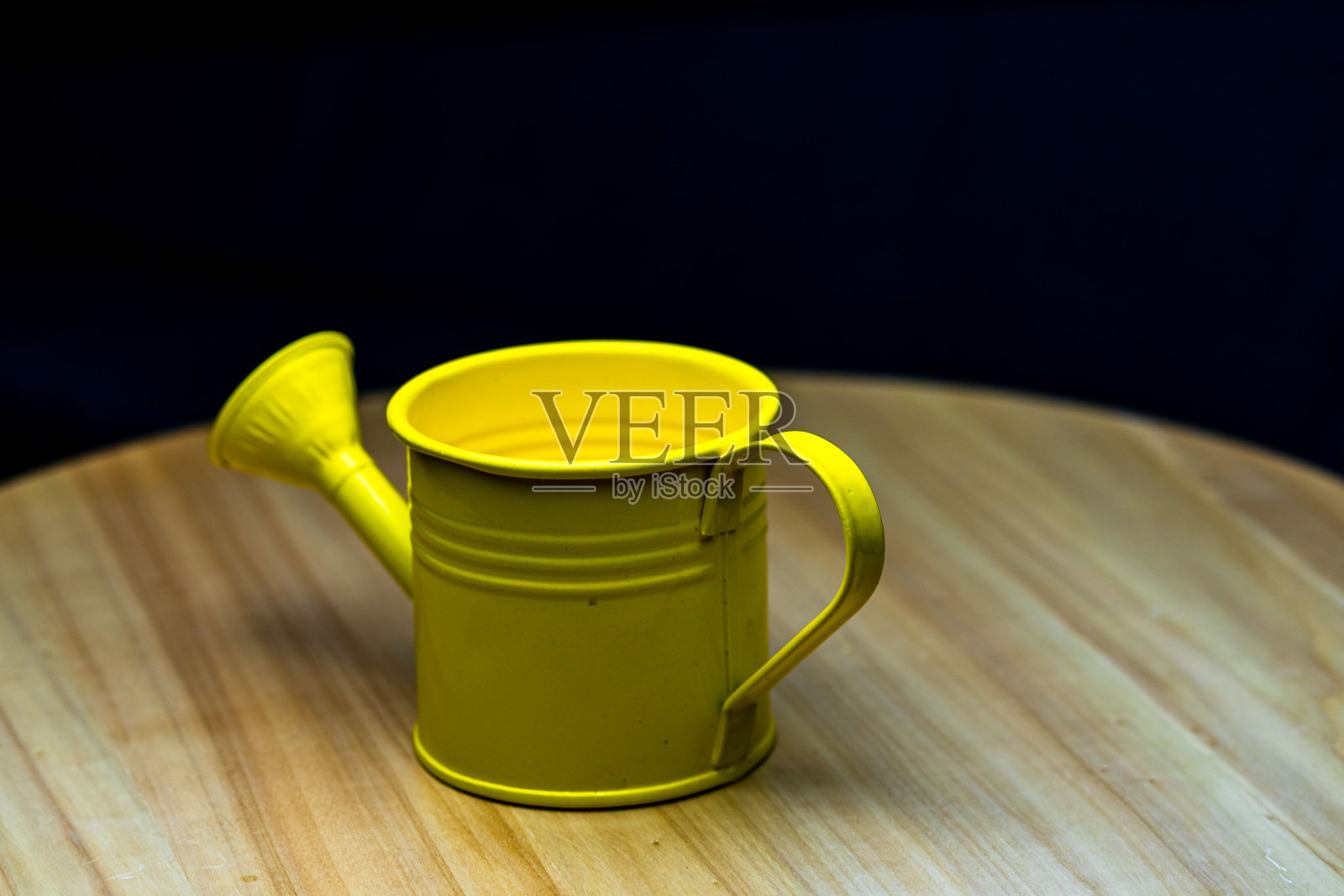 木桌上的一个小金属黄色喷壶的特写镜头照片摄影图片