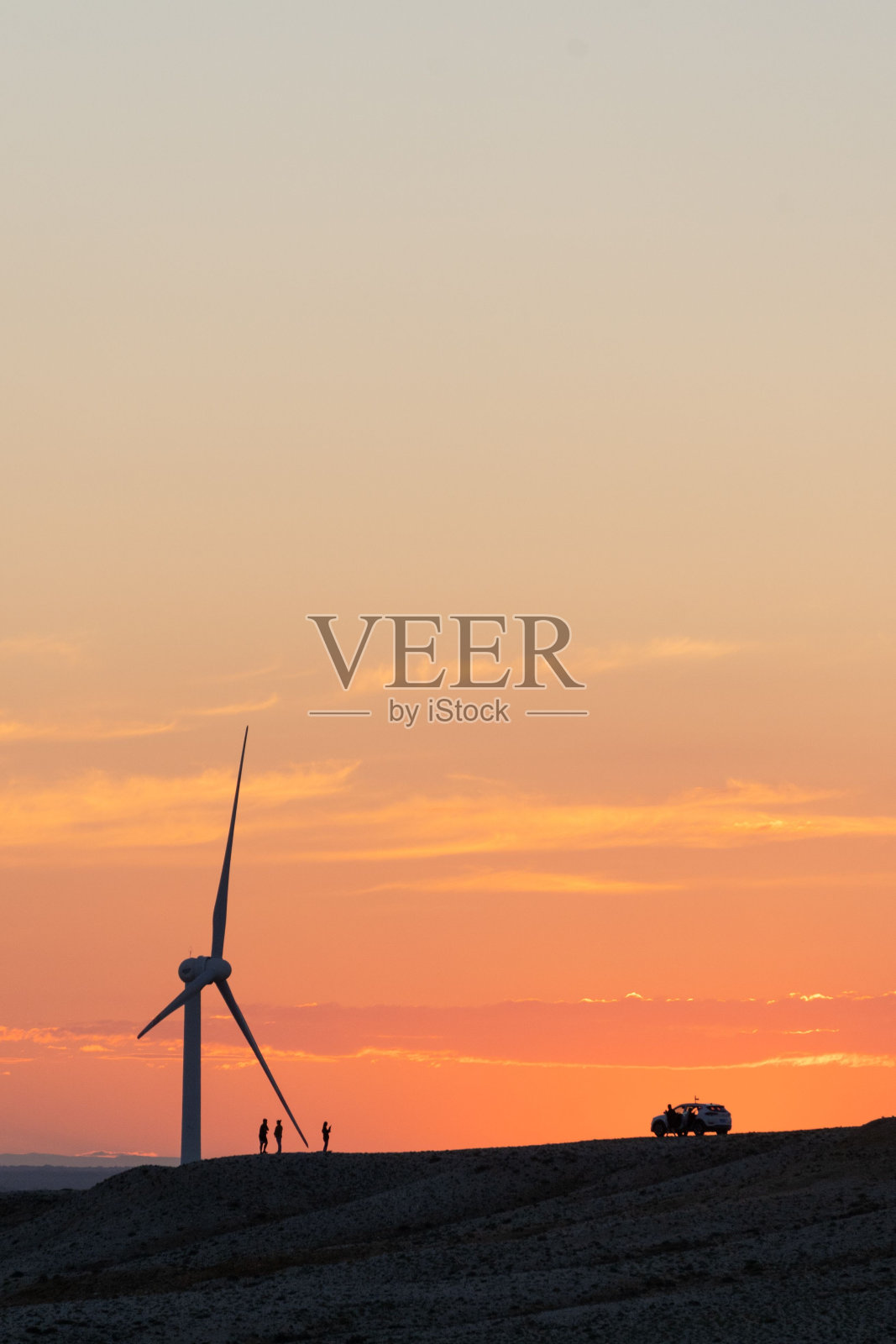 垂直拍摄的剪影的风车在草地上在一个戏剧性的日落天空照片摄影图片