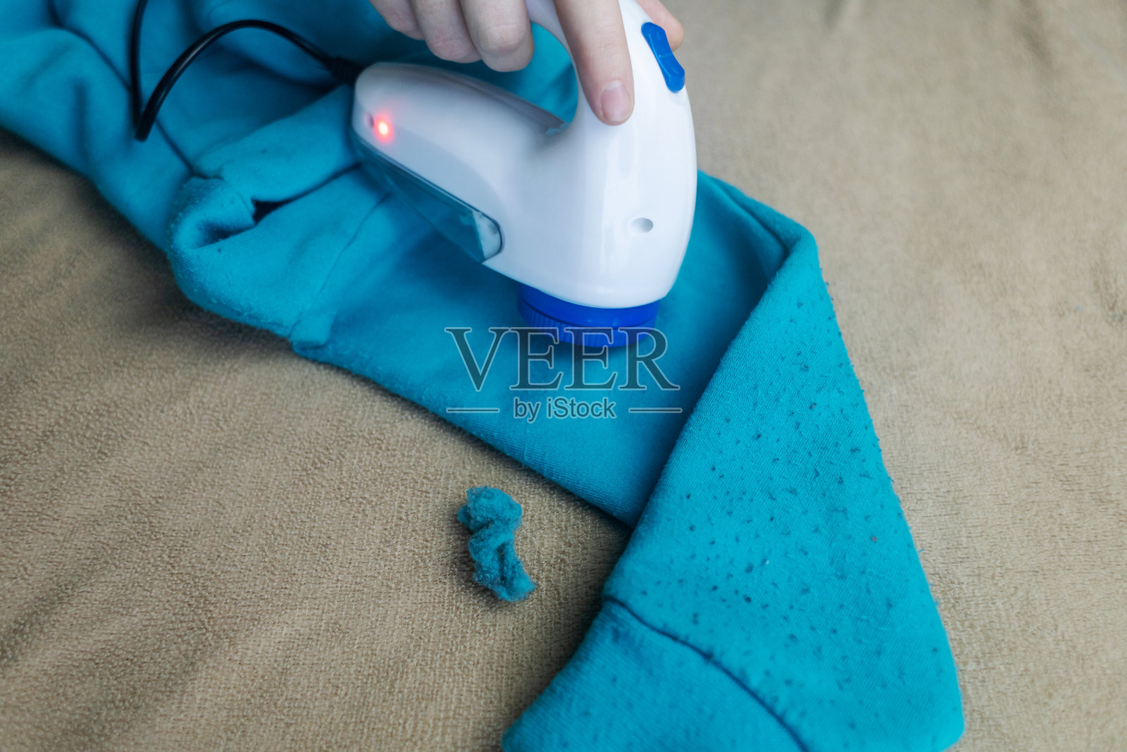 去除颗粒的机器。这个女孩用一种特殊的装置去除衣服上的棉绒。修复旧的损坏的衣服。照片摄影图片