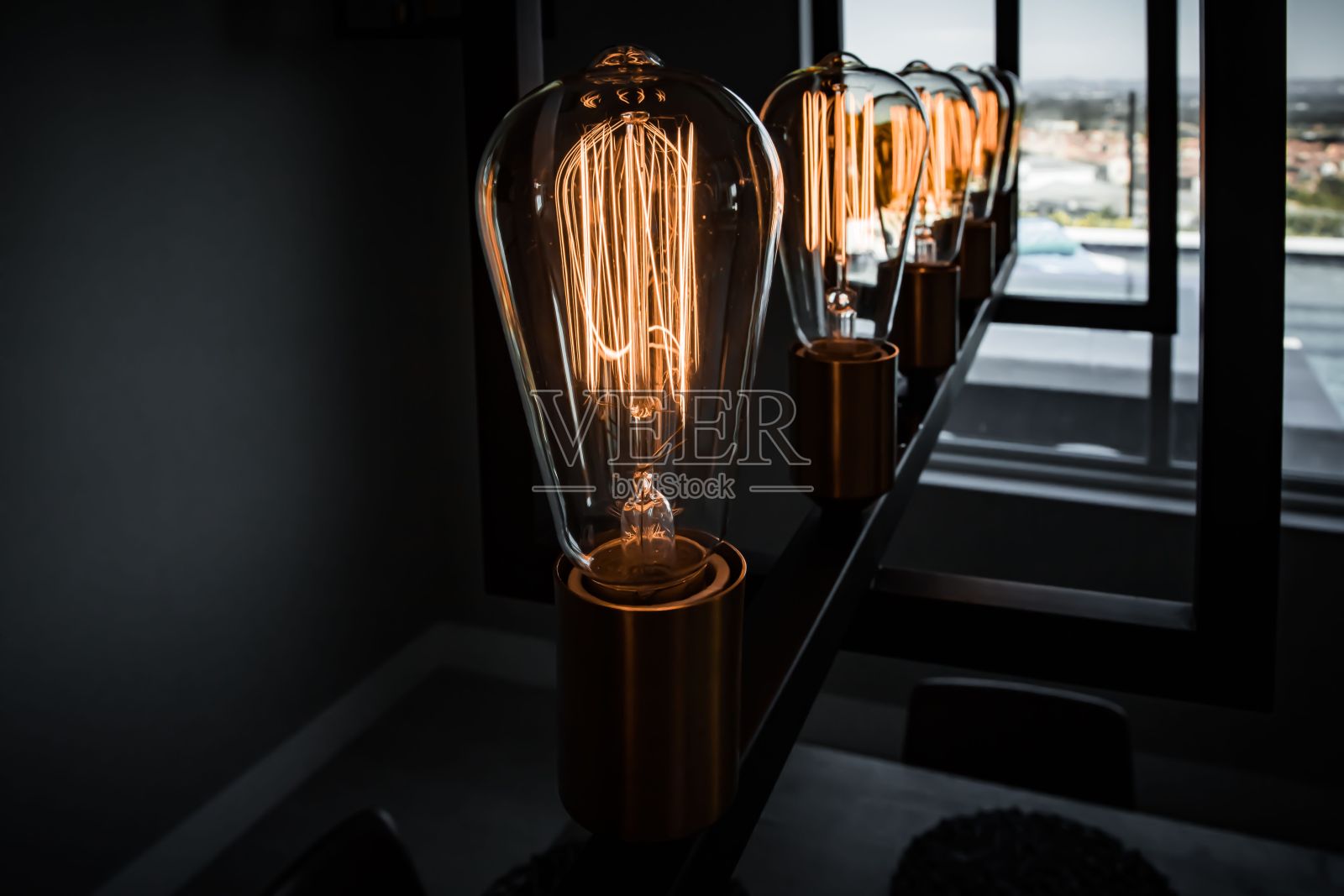 近景现代灯泡在当代吊灯与黑暗模糊的背景照片摄影图片