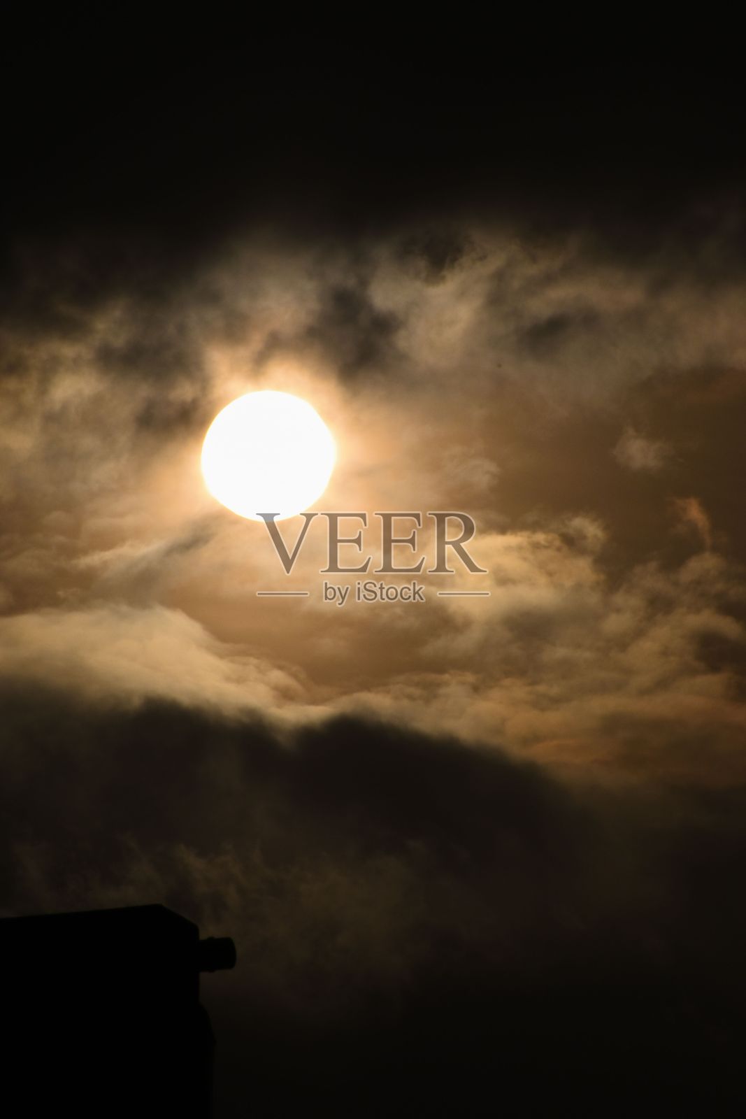 太阳在多云天空中的垂直镜头。照片摄影图片