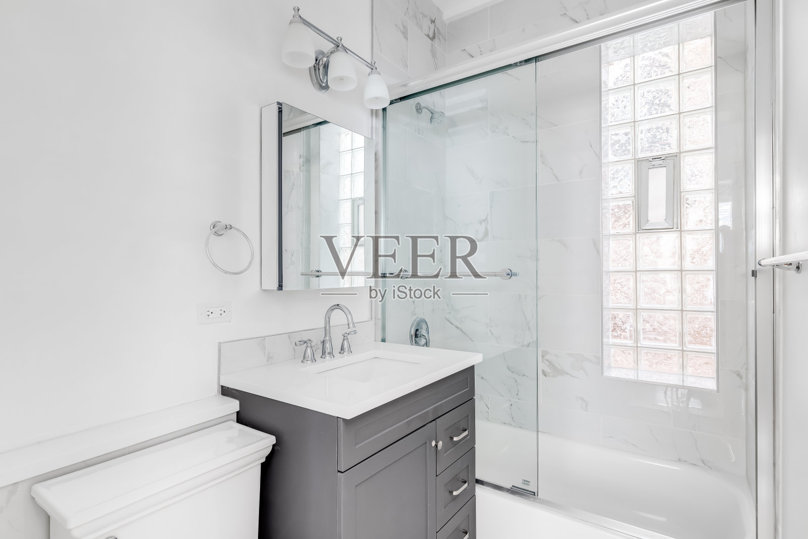 一间带灰色橱柜和大理石淋浴的浴室。照片摄影图片