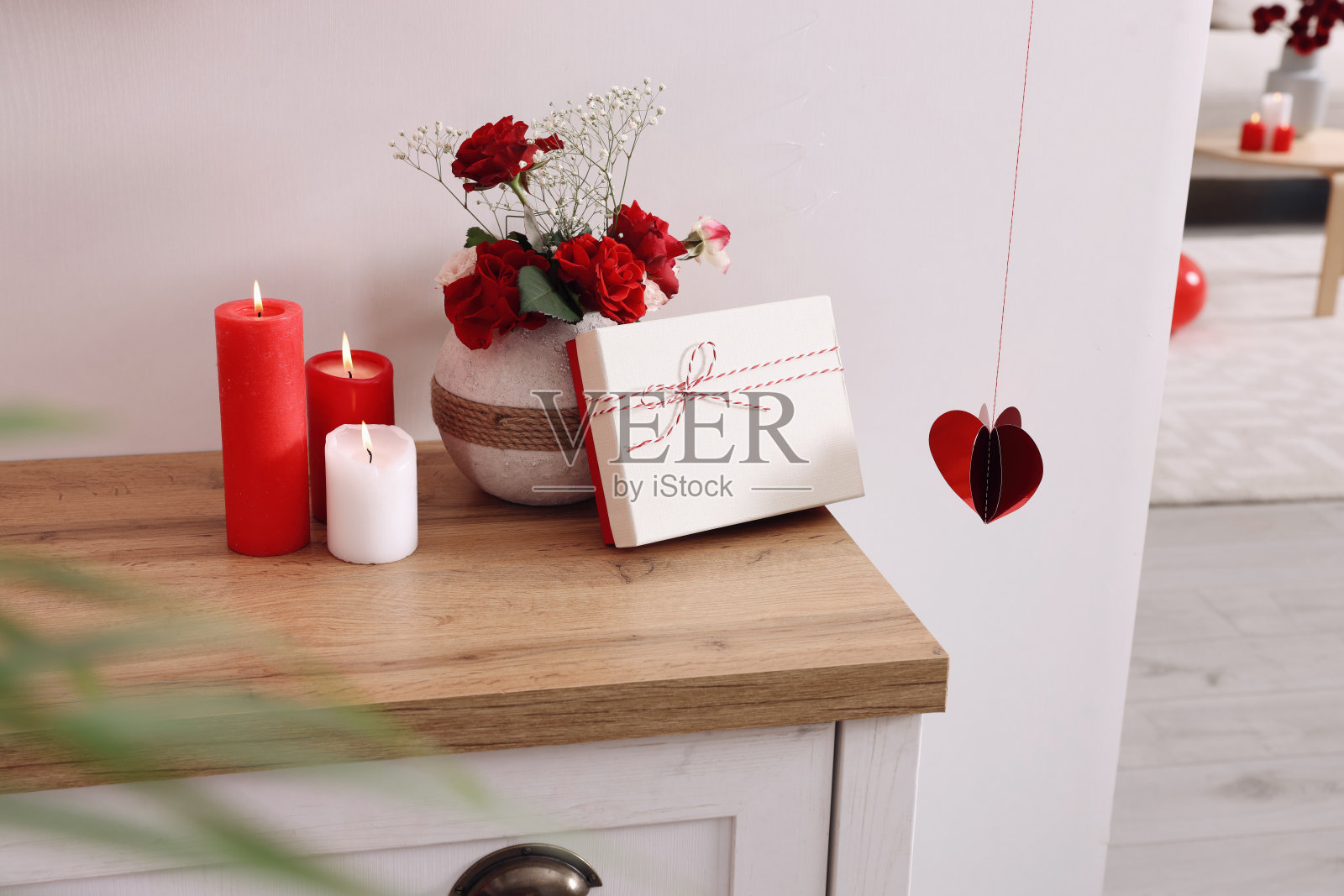 花瓶，漂亮的花，礼盒和蜡烛在室内的木桌上。情人节快乐照片摄影图片