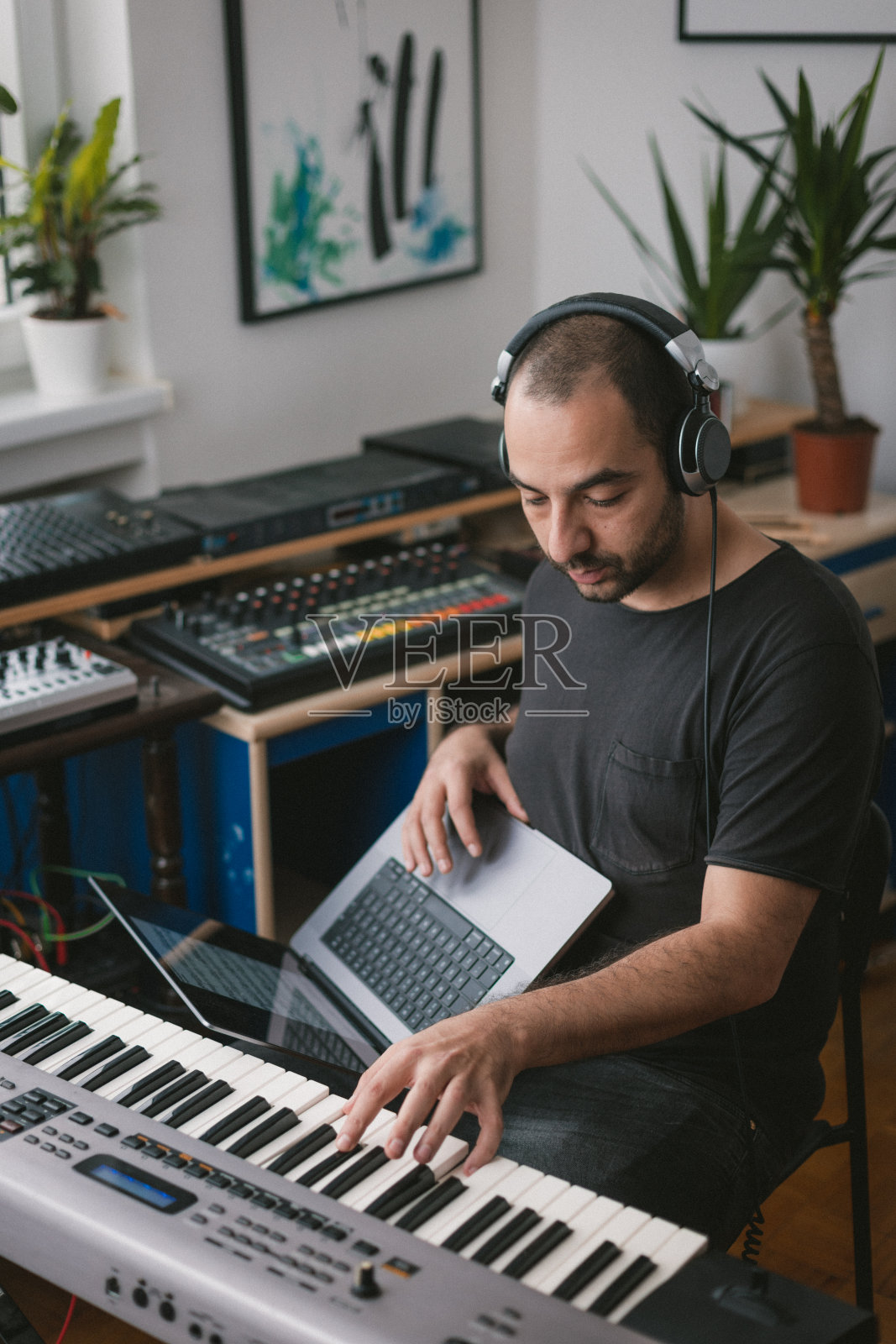 年轻人坐在家里的椅子上
戴着耳机，弹钢琴照片摄影图片