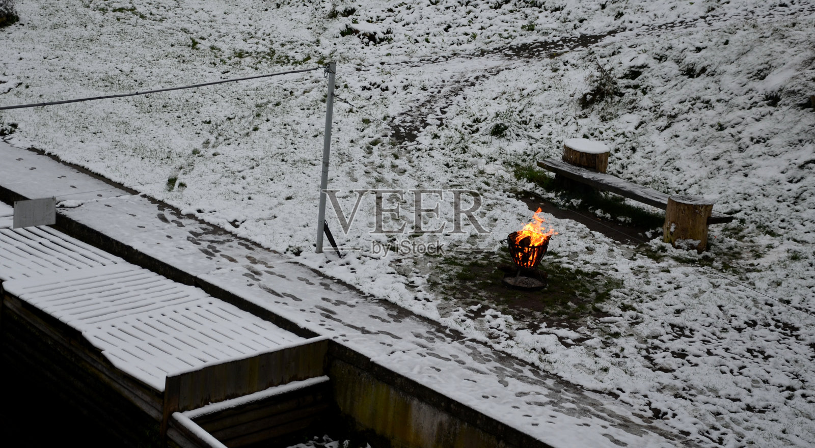 对于无家可归者和渔民来说，冬天的日子很难熬。金属篮子里装满了燃烧的木头。在港口池塘边的河岸上。,码头照片摄影图片