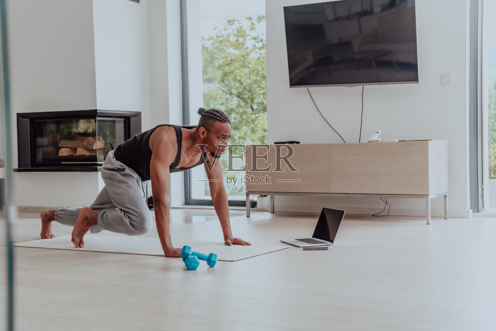 在家训练。运动男人一边训练一边在笔记本电脑上看在线教程，在客厅锻炼，自由空间照片摄影图片