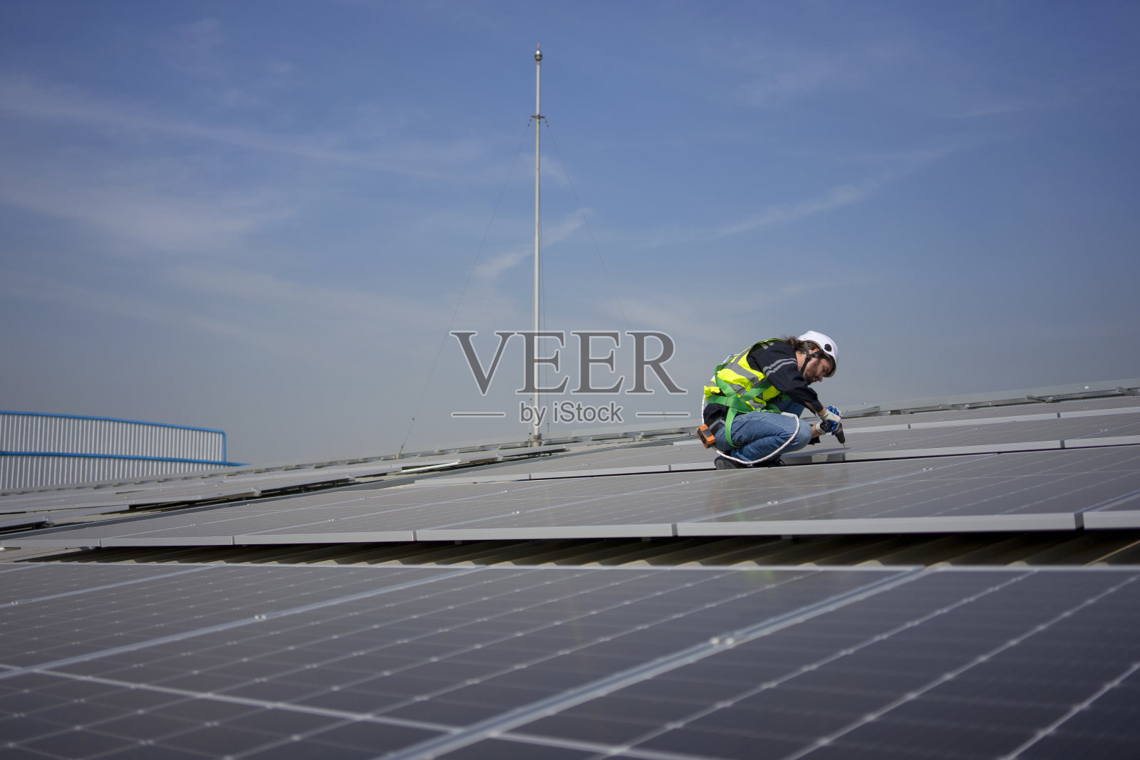 蓝领工人在屋顶安装太阳能电池板。照片摄影图片