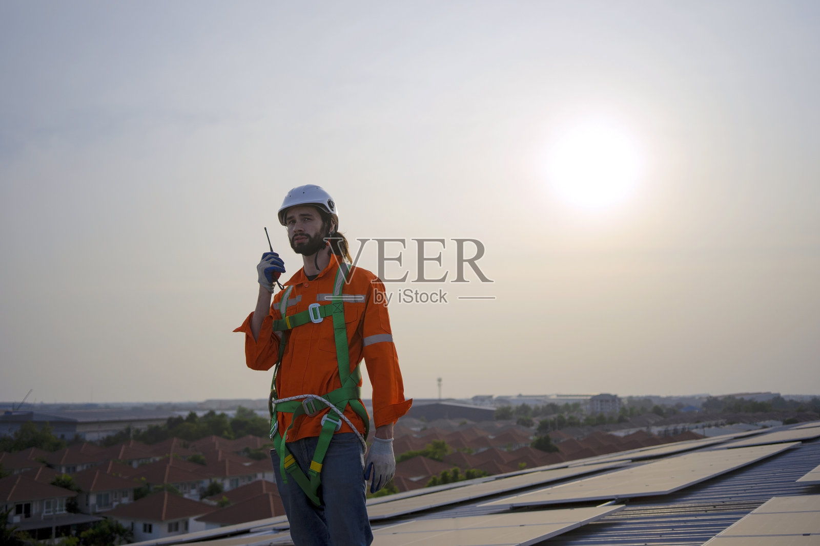 蓝领工人在屋顶安装太阳能电池板。照片摄影图片